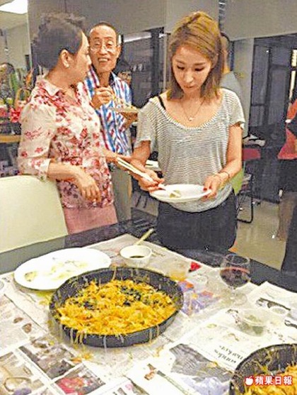 萧亚轩（右）在石家餐桌旁夾取食物。