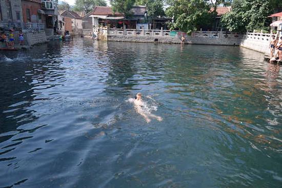 泉池中游泳健身的老人