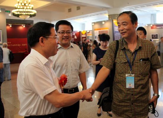民革中央副主席傅惠民与老兵拍摄者、团结报记者刘洪握手