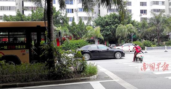 南宁市双拥路，一辆公交车在斑马线前停车礼让，旁边车道的私家车却抢先驶过。