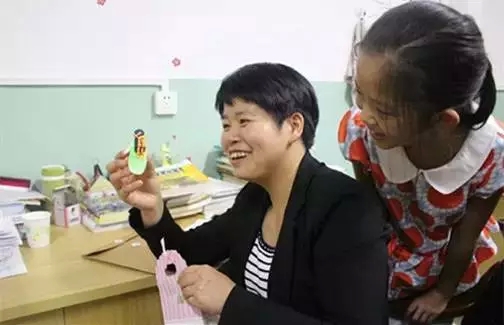 ▲9月11日中午，段雪梅拿出一学生送给她的礼物，一个彩泥娃娃给其他学生看。