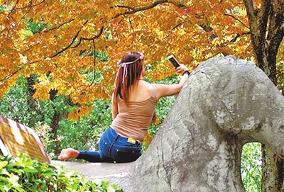 南京中山陵风景区明孝陵石象路上，一女子骑在有着600多年历史的文物上玩自拍。