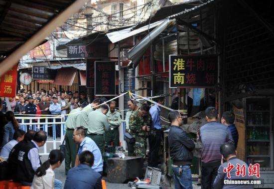 10月11日，芜湖杨家巷发生爆炸的店铺被封锁，现场消防、警察正在进行清理店铺等工作。中新社记者 韩苏原 摄