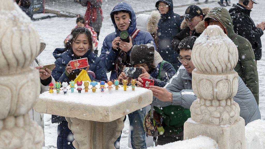 ▲2019年2月14日，北京，一些游人和摄影师在雪中摆上故宫文创产品中的动漫角色拍照。图/视觉中国