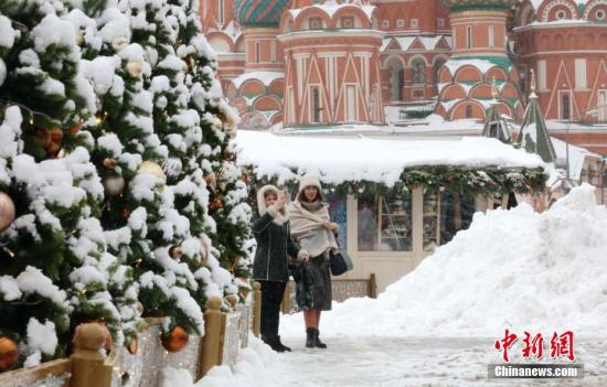  资料图：两名俄罗斯民众站在白雪覆盖的红场上，其中一人用手机拍摄雪景。 中新社记者 王修君 摄