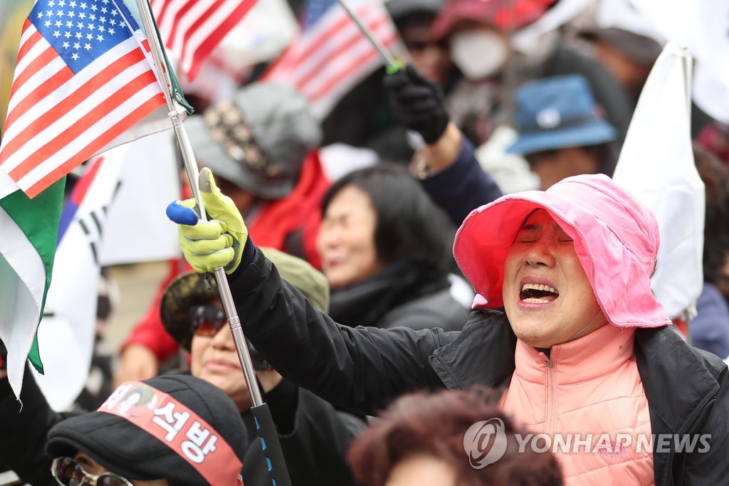 朴槿惠支持者手持美国国旗据韩联社4月6日报道,韩国首尔中央地方法院
