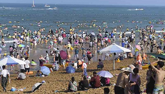 山东日照：高温酷暑 游客下海避暑如同下饺子。 图片来源：视觉中国