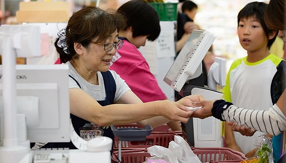 &nbsp;8月4日,东京一家超市,一名老年收银员为顾客结账.