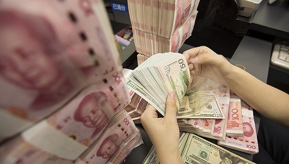 在江苏省南通海安市一家银行内,银行工作人员在清点人民币和美元现钞