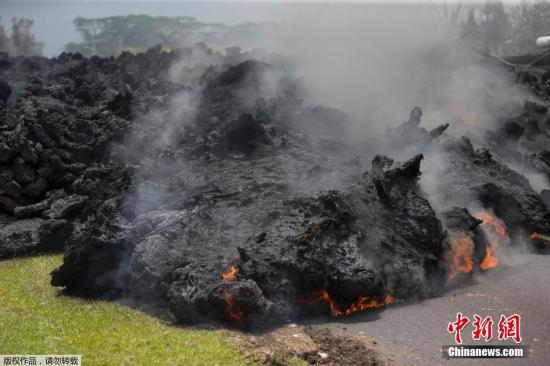图为阻断道路的熔岩仍在不断燃烧。