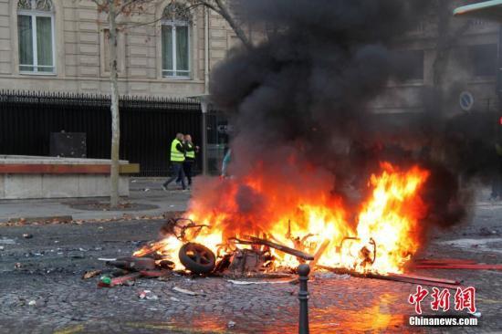 当地时间11月24日，巴黎香榭丽舍大街遭遇大规模示威活动。数以千计示威者聚集在街上，设置了不少路障，街道交通完全陷入瘫痪。图为示威者在香榭丽舍大街附近点燃的大火。中新社记者 李洋 摄