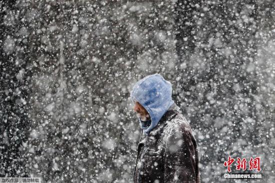 图为行人走在暴风雪肆掠的费城街头
