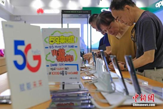 Data map: People handle 5G mobile phone and network related services. Photo by Yin Liqin