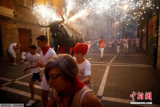  资料图片：西班牙潘普洛纳，西班牙圣佛明节第三天，狂欢者与由人扮演的“公牛”上演惊险追逐战。
