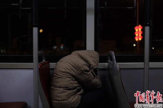 深夜1点的公车上，一名青年和衣蜷缩在座椅上。中国青年报·中青在线记者 郑萍萍摄