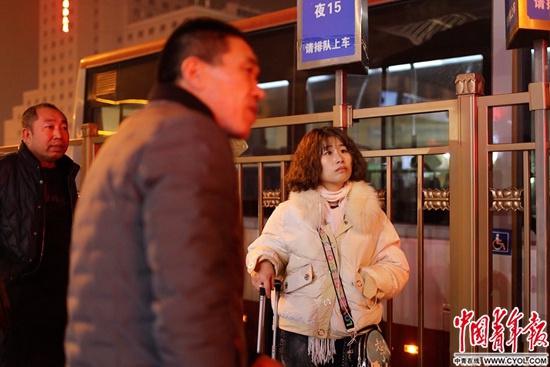深夜抵达北京西站的乘客，查看夜班车线路。中国青年报·中青在线记者 郑萍萍摄