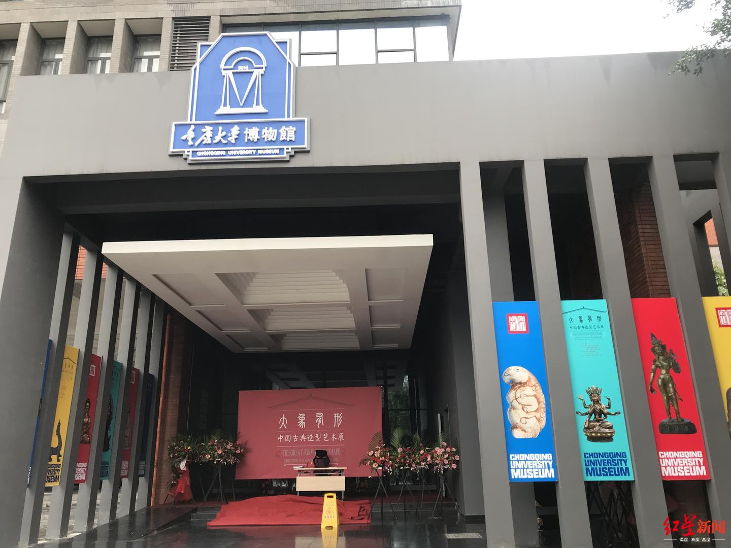 重庆大学博物馆的花篮和红毯或因为下雨的原因收进了屋檐下的门口，保安将桌椅摆在门口