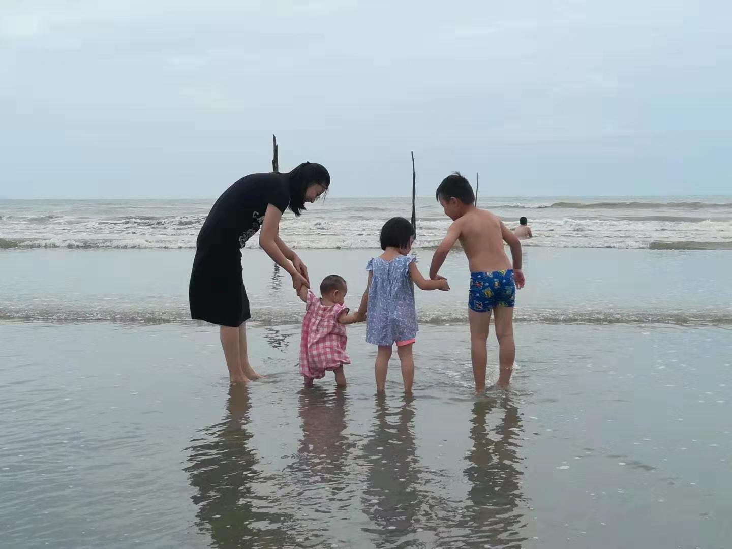 谢峥玲和孩子在海边游戏。受访者供图