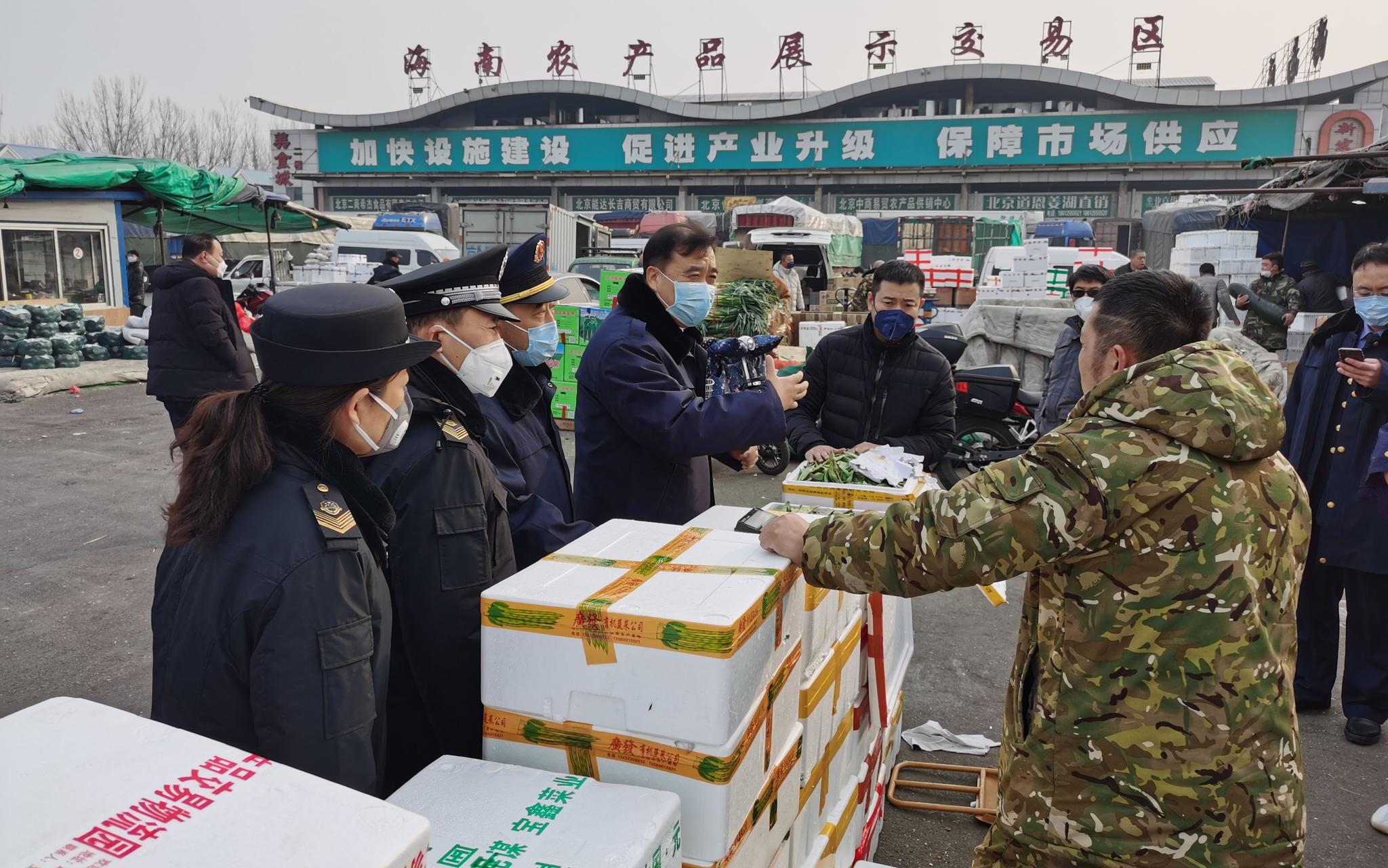 新发地市场工作人员询问菜价。新京报记者 王颖 摄