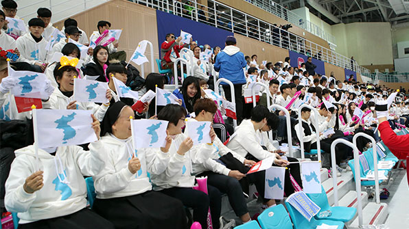  朝韩联合拉拉队手举统一旗，为朝鲜队加油助威。（韩国KBS新闻）