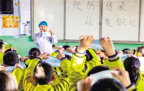 河北衡水市武邑县医务人员向聚英学校学生演示口罩正确佩戴方法。 经济日报 图