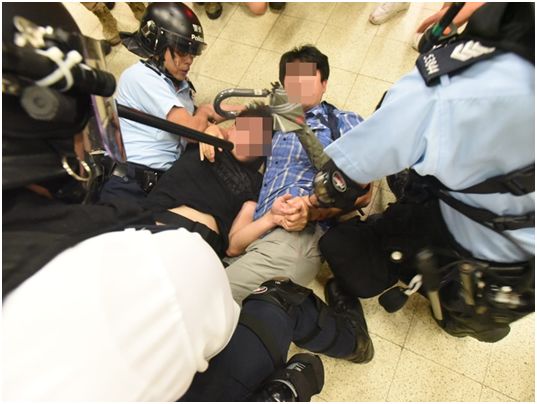 身穿蓝色格子衫的香港市民协助港警制服暴徒。来源：港媒