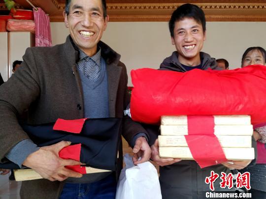 图为李吉胜(左)和幼儿子准备向女方送彩礼。 张增福 摄