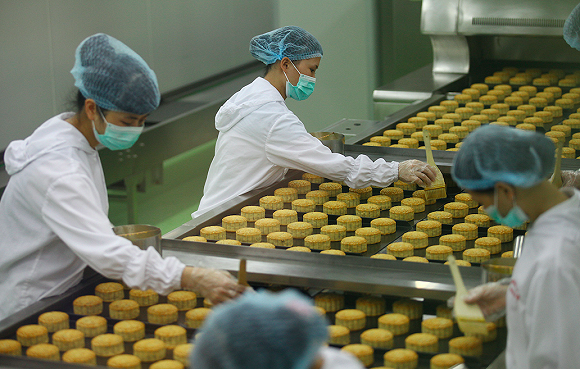 月饼工厂里女工正在给月饼刷油.