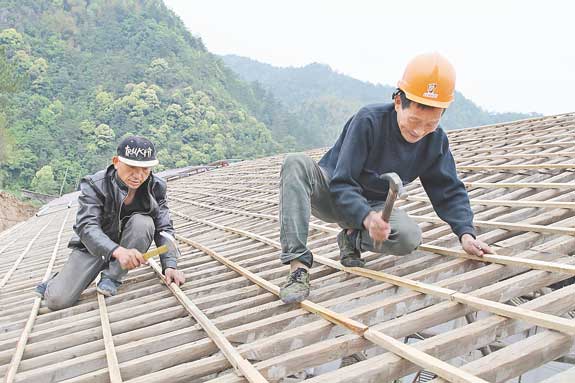 原来是几位木匠师傅正爬在屋顶上给房子钉木条子