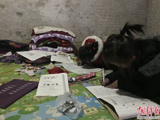 1月4日,张欢张圆姐妹正趴在床上写作业。中国青年报·中青在线记者 孙庆玲/摄
