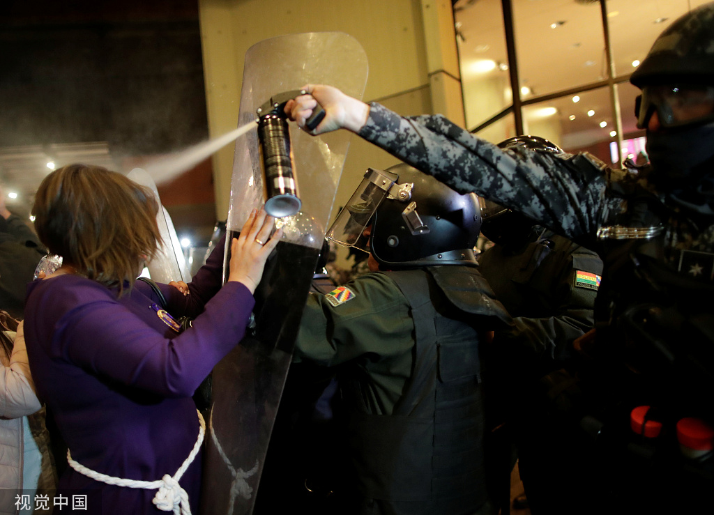  10月21日，玻利维亚拉巴斯，一名防暴警察向示威者喷胡椒水。图自视觉中国