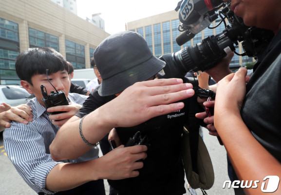  24日，涉案男子接受警方调查，遭媒体围堵（韩联社）