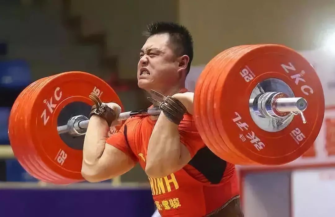 员将杠铃平行地放在两小腿前面   以一个连续动作把杠铃从举重台上