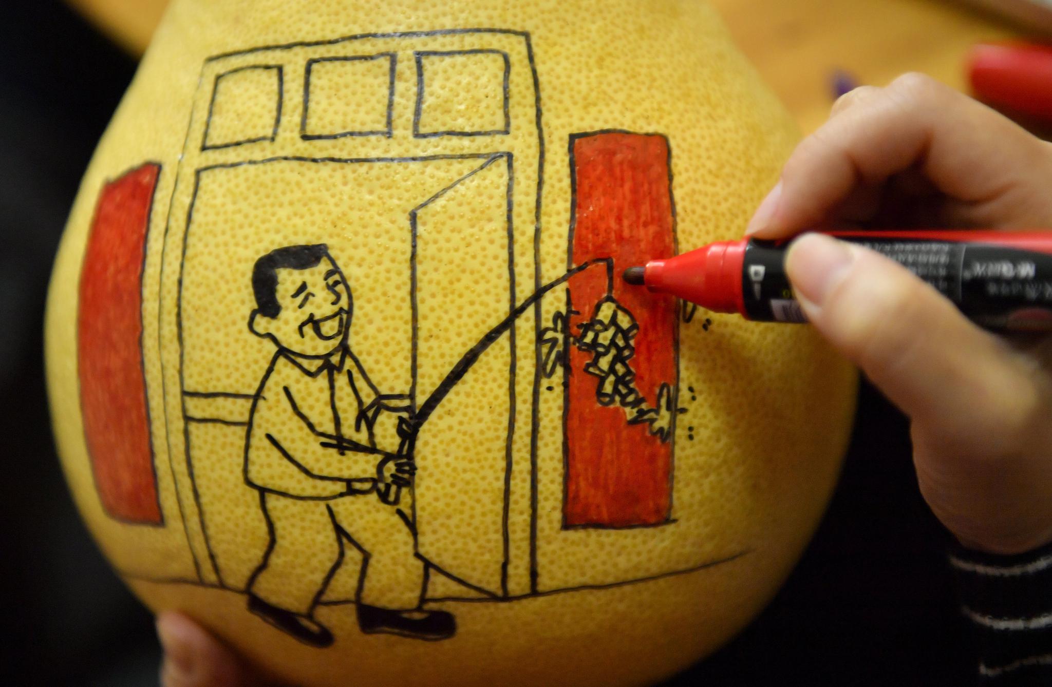 收获期,当地合作社的社员在柚皮上手绘各种图画,让柚子变得俏皮可爱