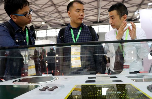 2018国际半导体展上，一位工作人员（右）在展会现场向参观者介绍一组芯片切割样品。（新华社）