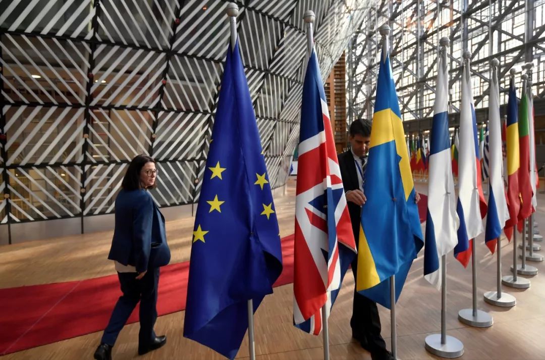 10月17日，在位于比利时布鲁塞尔的欧盟总部，一名工作人员在欧盟峰会前整理旗帜。新华社/路透