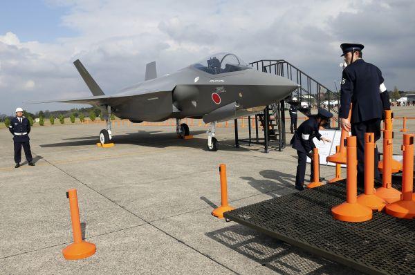 这是在日本东京以北的茨城县百里基地，日本航空自卫队人员在F-35战斗机模型旁设置警戒线的资料照片（2014年10月26日摄）。新华社/美联