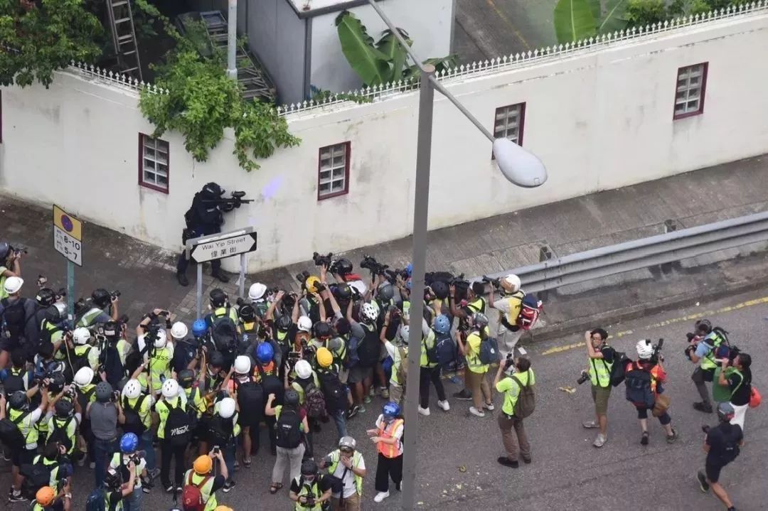 一名手持胡椒球发射器的港警瞄准暴徒，几十个港媒记者却将镜头对准了他（图源：港媒）