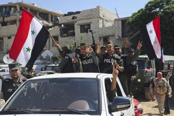 图为叙利亚警察在该地区挥舞国旗.(美联社)