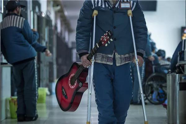 1 月 8 日，湘南监狱十一监区，一名腿脚不便但很喜欢音乐的服刑人员，走到哪都抱着吉他，他还把自己的经历写成一首山歌在监舍弹唱。 杨旭 图