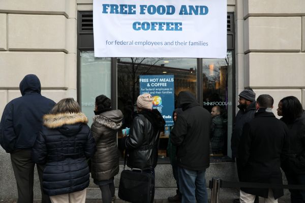 受美国政府关门影响的联邦雇员16日在华盛顿排队领取由非营利组织提供的免费食物和咖啡。（路透社）