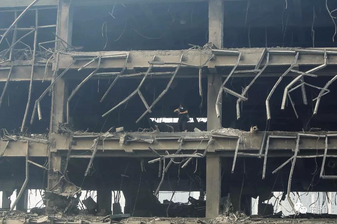  △ 2015年8月15日，天津滨海新区“8·12”爆炸现场，新京报记者尹亚飞正在一栋被炸毁的大楼内拍摄。摄影/彭子洋