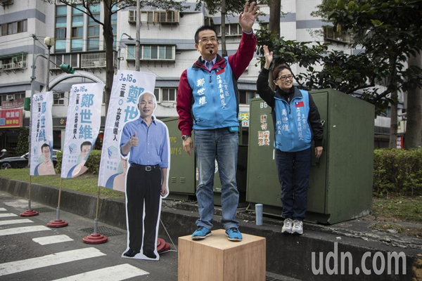  国民党三重“立委”补选候选人郑世维和妻子，今（11日）上午7点在忠孝桥头，请出高雄市长韩国瑜的立牌向民众致意。（图片来源：台湾《联合报》）