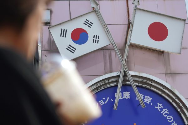 资料图：在日本首都东京的新大久保，行人从标有日本和韩国国旗的广告牌前走过。（新华社）