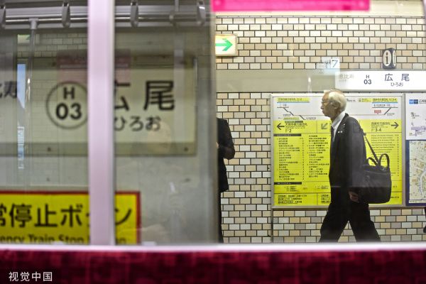 资料图片:当地时间2018年10月16日,日本东京的一处地铁站内,一位西装革履的老年人背着公文包匆匆走过。(视觉中国)