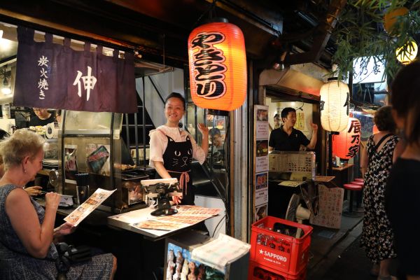  夜幕下的日本东京，一位店家正在招揽顾客。（新华社）