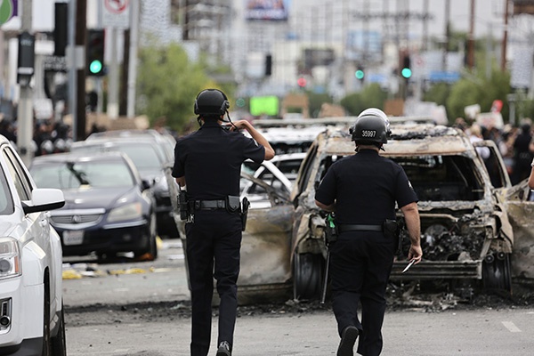 5月30日，在美国洛杉矶，警察走向被烧毁的车辆。新华社 图