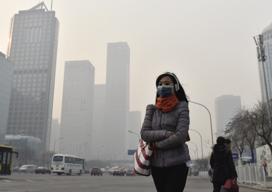 一名戴口罩的行人在雾霾下的北京街头行走.新华社发