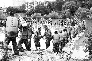7月5日，湖北某预备役高炮师官兵在传递袋装石料，用于管涌处置围堰修筑。新华社发