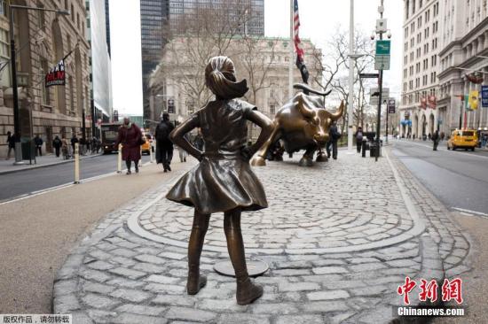  资料图：华尔街上，“无所畏惧的女孩”铜像双手叉腰，面朝著名的华尔街铜牛。
